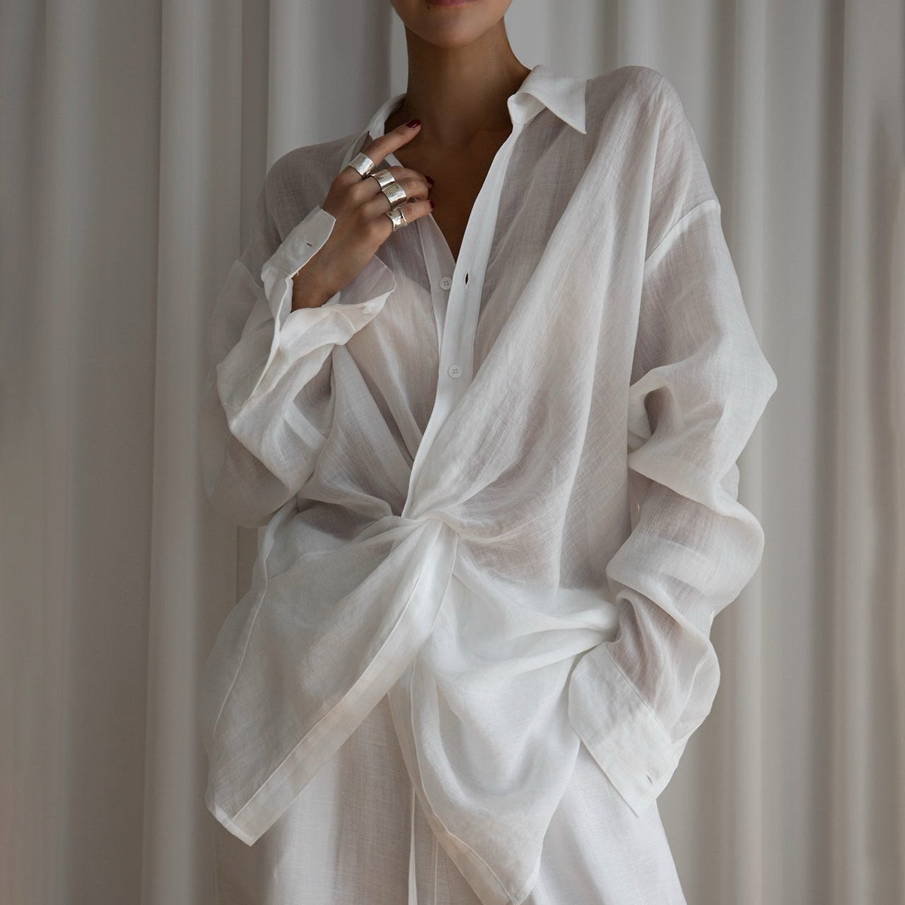 Person wearing a white linen shirt and pants against a neutral background