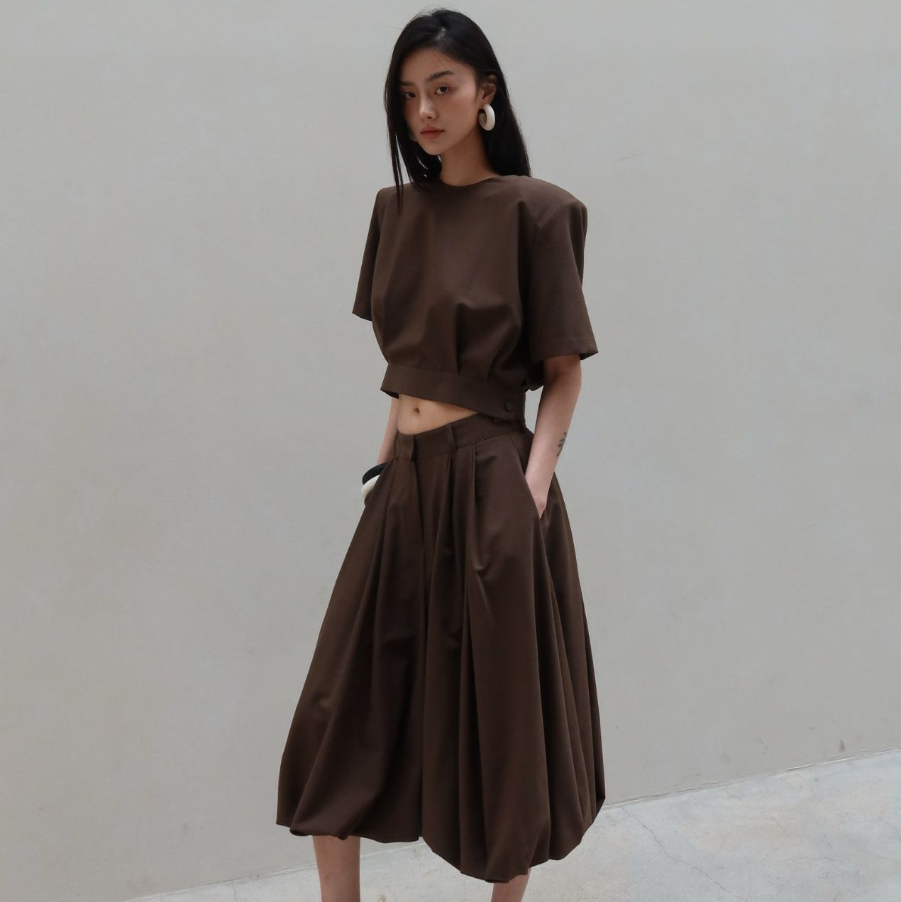 Woman wearing a brown outfit against a plain background
