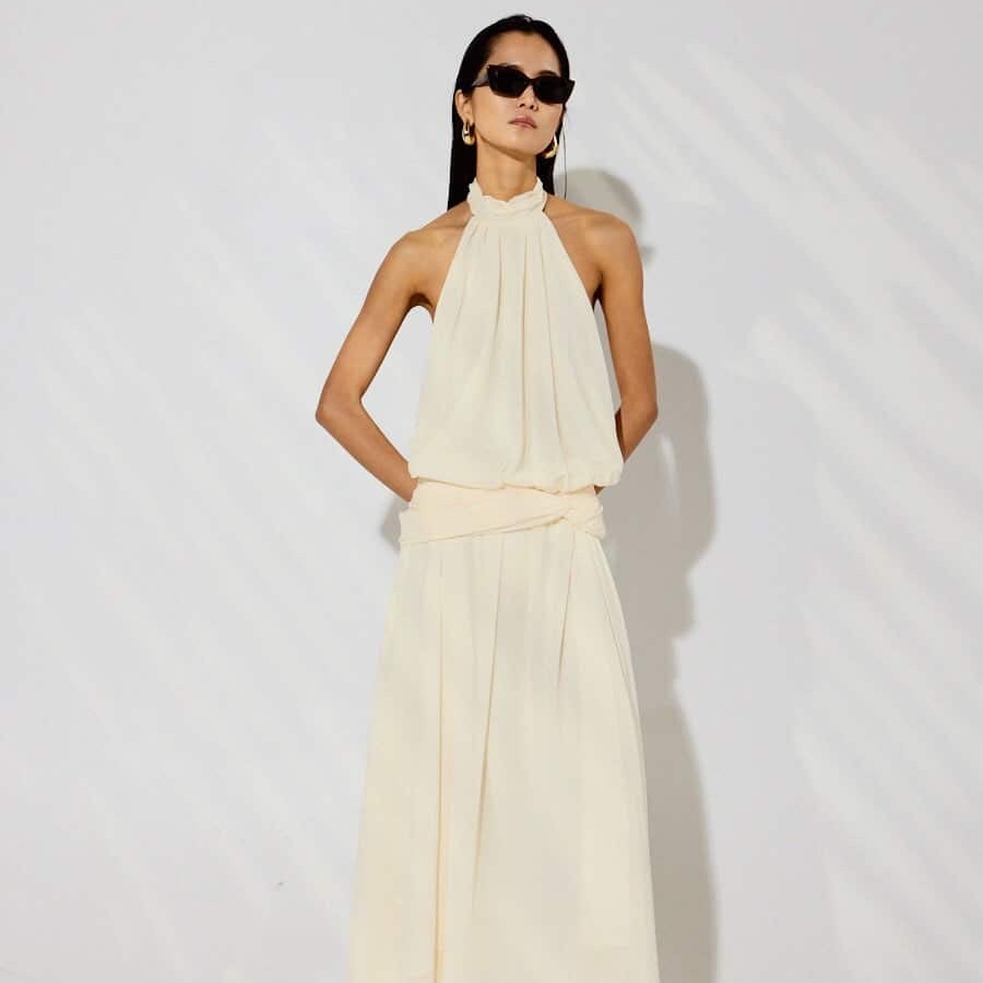 Woman wearing a flowing white dress against a plain background