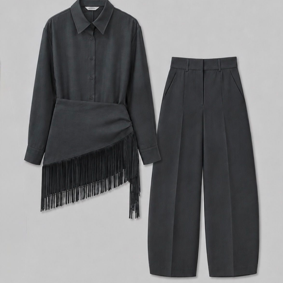 A dark charcoal gray two-piece outfit consisting of a long-sleeve collared shirt with an asymmetrical wrap detail and fringe, paired with high-waisted cropped trousers, shown on a neutral gray background.