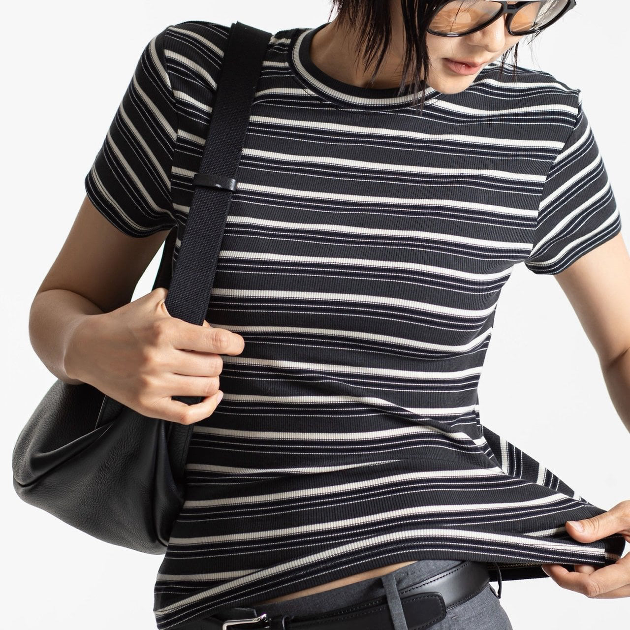 Person wearing a black and white striped shirt holding a black bag.