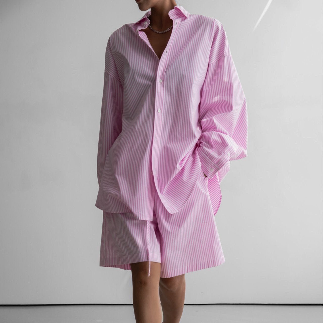 Person wearing a pink striped shirt and skirt set on a white background