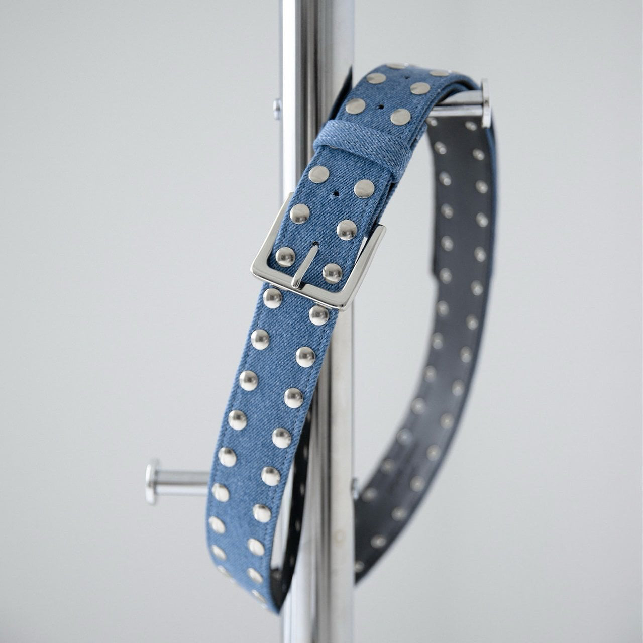 Blue denim dog collar with silver studs on a stand against a light gray background