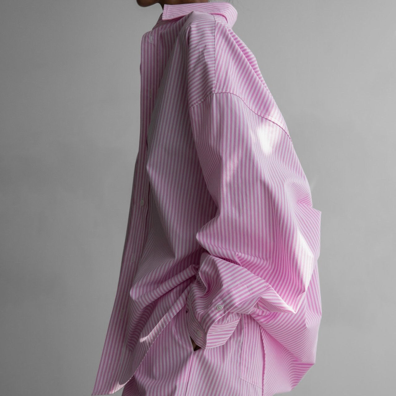 Pink striped shirt with a bow detail on a gray background