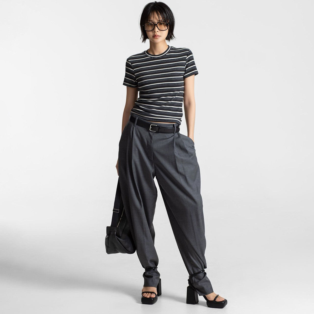 Person wearing a striped shirt and gray pants on a white background