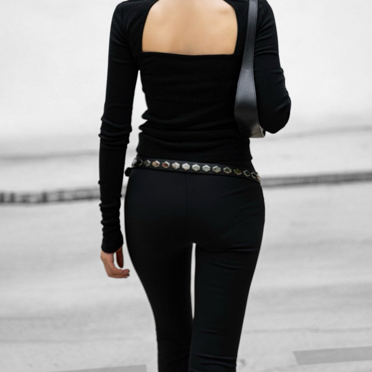 Person wearing a black outfit with an open back design on a light gray background
