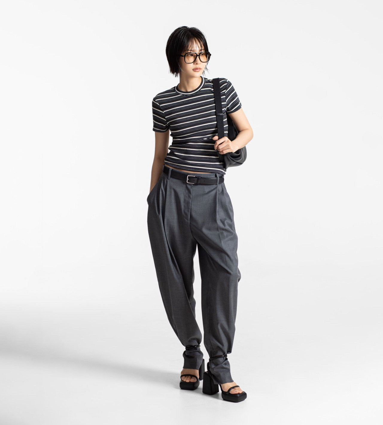 Person wearing a striped shirt and gray pants on a white background