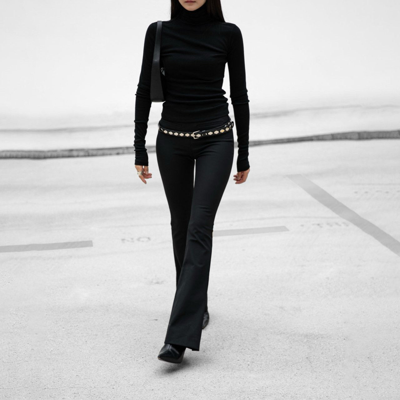 Person wearing a black outfit with a belt on a snowy background