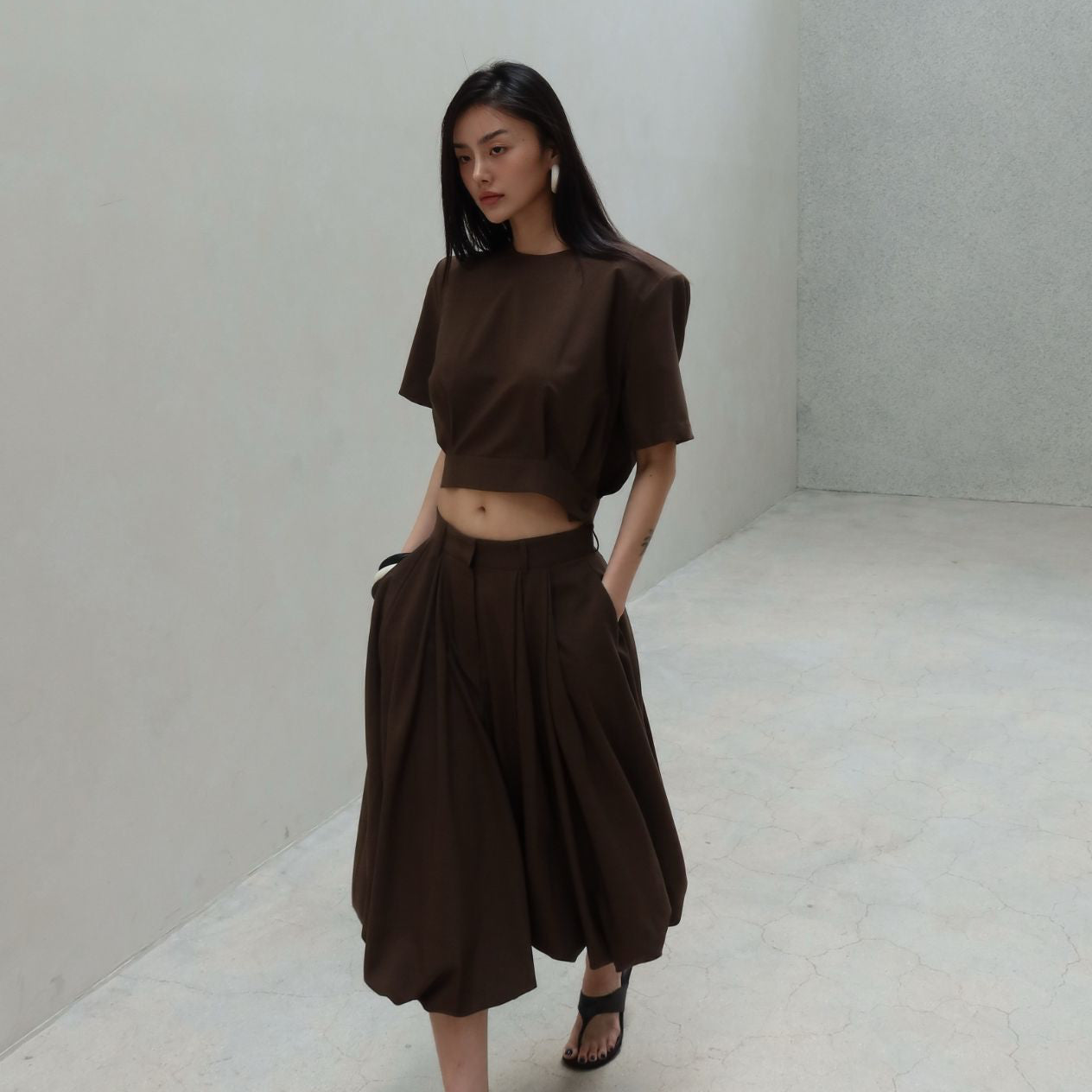 Woman wearing a brown outfit in a minimal white room