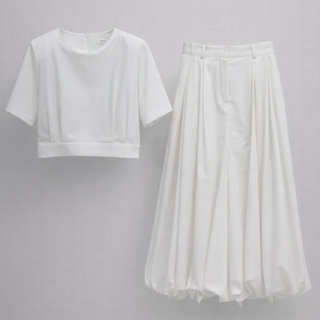White crop top and flowing white skirt on a gray background